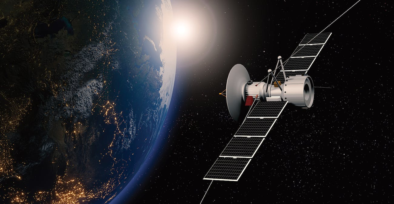A satellite with large solar panels orbits Earth, which is partially illuminated by sunlight. City lights are visible on the planet’s surface, while a Standex Edge power inductor ensures reliable operation against the dark backdrop of space. by Standex Edge