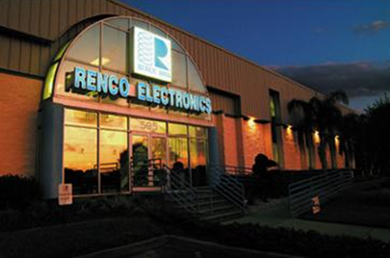 A glass-fronted building with a large RENCO ELECTRONICS sign glows at dusk. Warm lights illuminate the interior, and palm trees line the walkway, reflecting the innovation behind their high frequency transformer solutions. by Standex Edge
