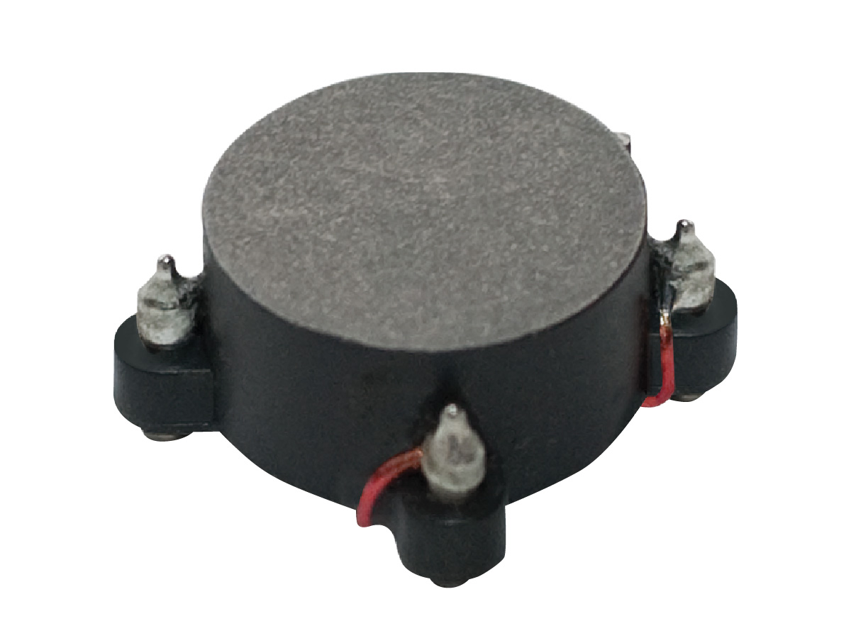 A close-up of a small, round electronic component with four metal pins and visible copper wire, likely a Standex Edge power inductor or transformer used in power magnetics applications. by Standex Edge