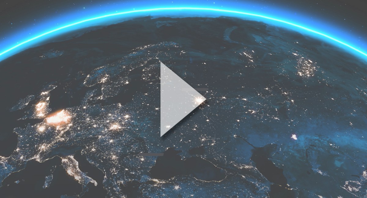 View of Earth from space showing illuminated cities at night across Europe and parts of Asia, highlighting the impact of Smart Grid technology, with a large transparent play button overlayed in the center. by Standex Edge