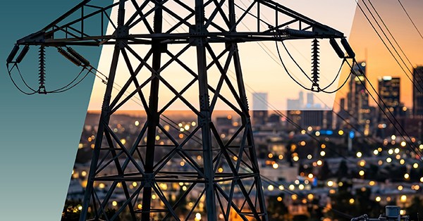 A close-up of a power transmission tower, highlighting the importance of clearance and creepage, with city buildings and lights in the blurred background at sunset. The image is partially divided with a teal overlay on the left. by Standex Edge