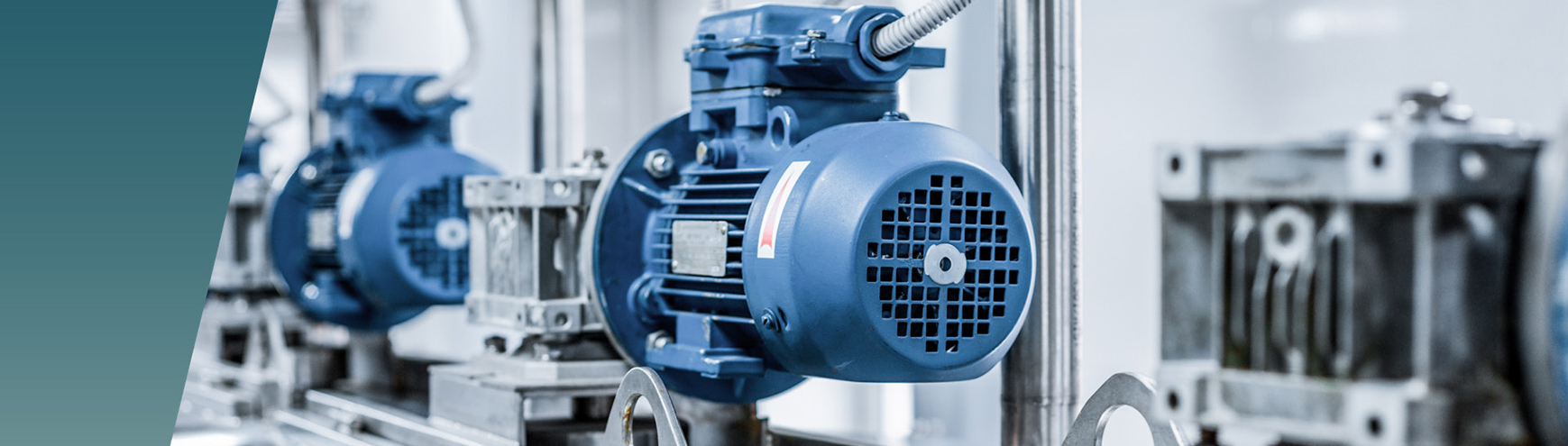 Close-up of a blue industrial electric motor installed on machinery in a factory setting, highlighting the careful consideration of clearance and creepage to ensure safe electrical operation, with similar equipment visible in the background. by Standex Edge